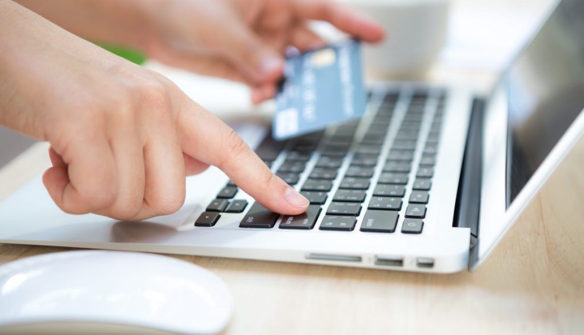 Hands holding a credit card and using laptop computer for online