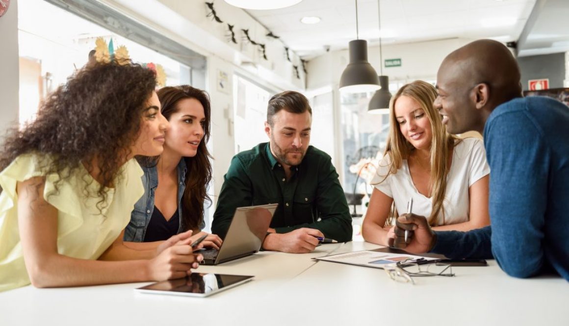 Multi-ethnic group of young people studying together on white de